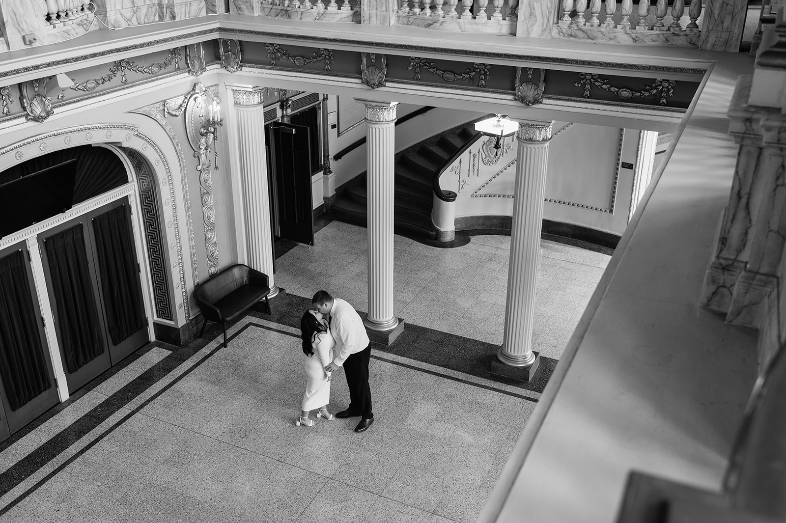 Black and white photo of a couple kissing inside the Morris Performing Arts Center.