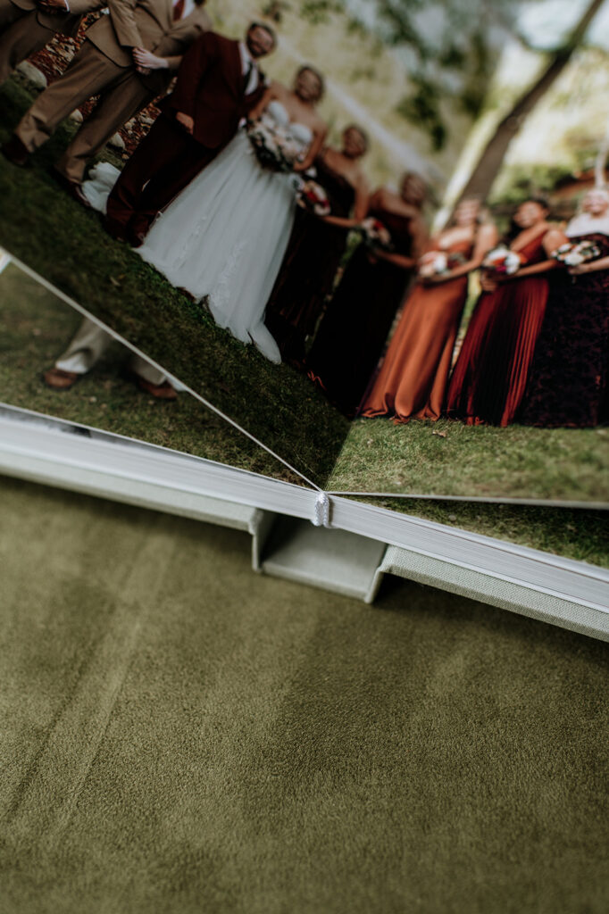 An open wedding album styled on a green surface.