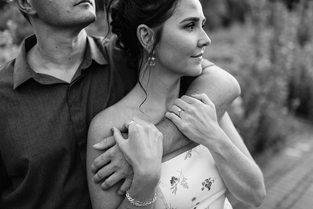 Black and white close up shot of a man with his arm wrapped around his fiancé during their engagement session.