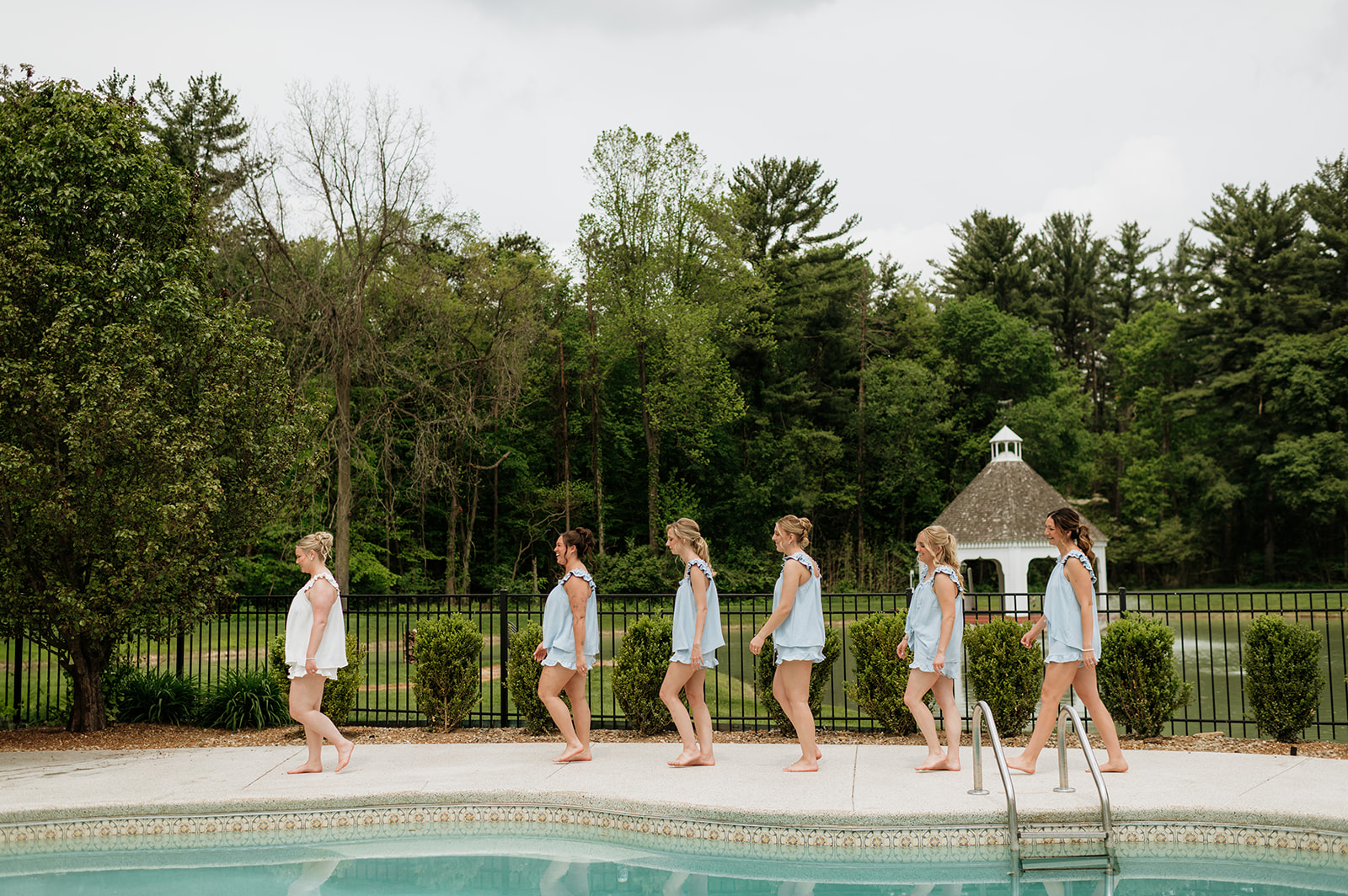 Bride and her bridesmaids walking in front of the pool at The Blacksmith Lodge at The Morris Estate in Niles, Michigan.