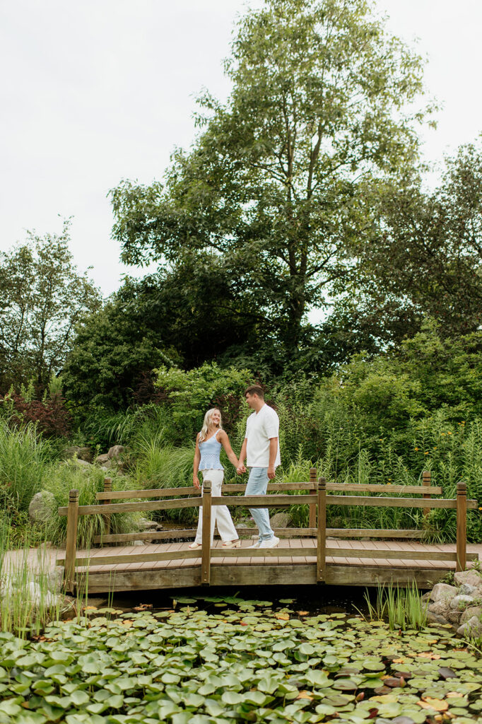 Couple walking over a bridge for their Cobus Creek County Park engagement photos near South Bend, Indiana.