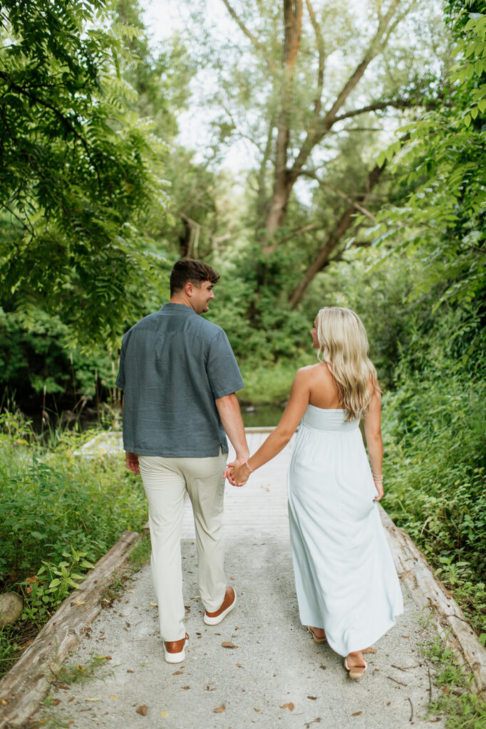 Couple walking hand in hand on a trail for their Cobus Creek County Park Engagement Photos in Elkhart, Indiana.
