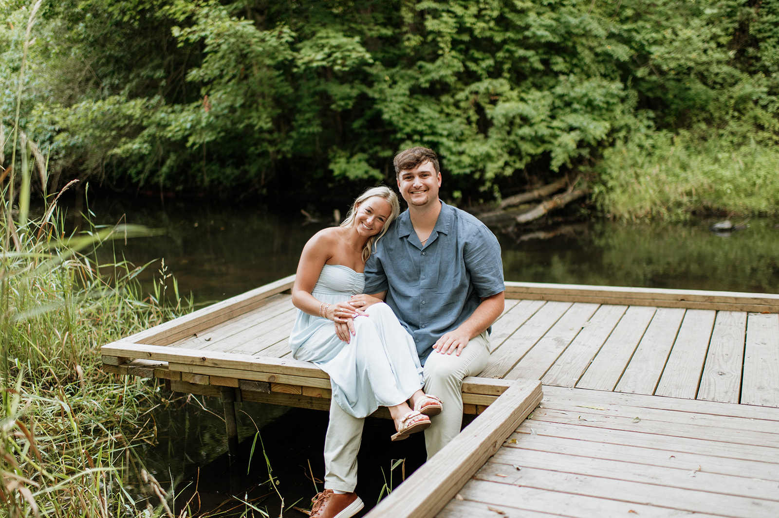 Couple sitting on a dock for their Cobus Creek County Park Engagement Photos in Elkhart, Indiana.