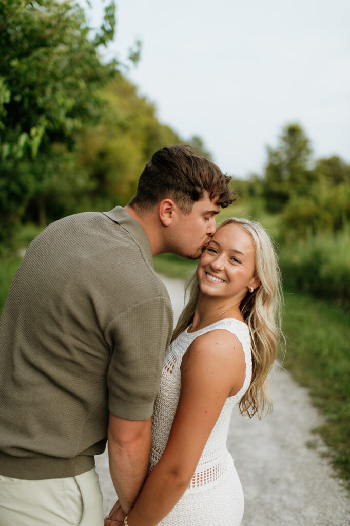 Man kissing his fiancés forehead during their outdoor engagement session.
