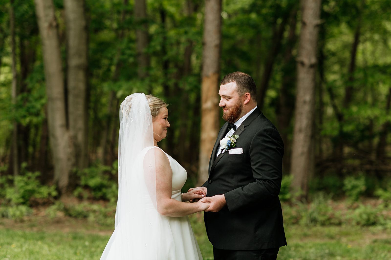 Bride and groom holding hands outdoors during their first look.