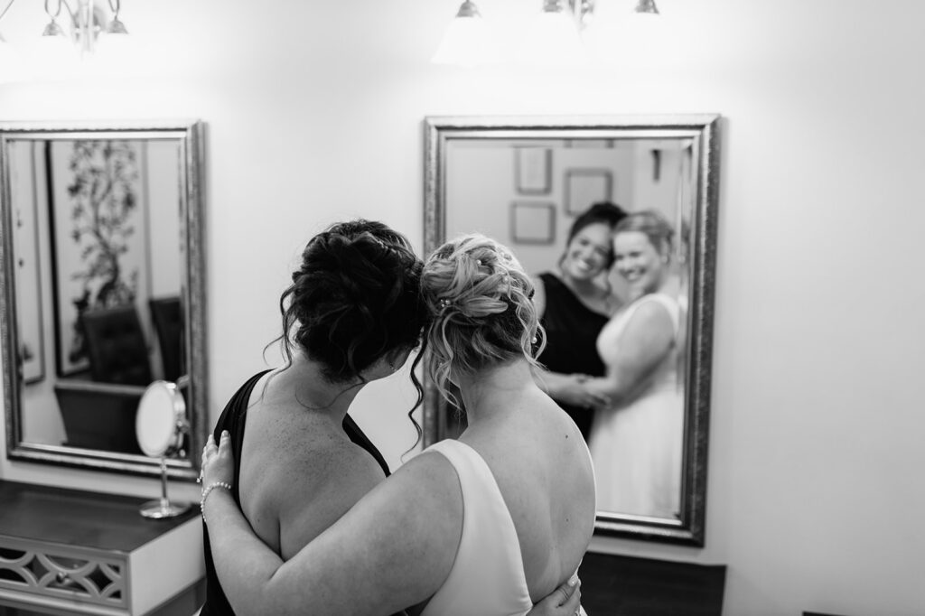 Black and white photo of the bride hugging a bridesmaids inside the Brides Lounge.