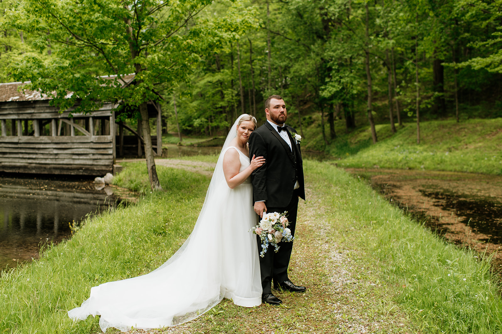 Bride and groom posing in front of the covered bridge at The Morris Estate in Niles, Michigan.
