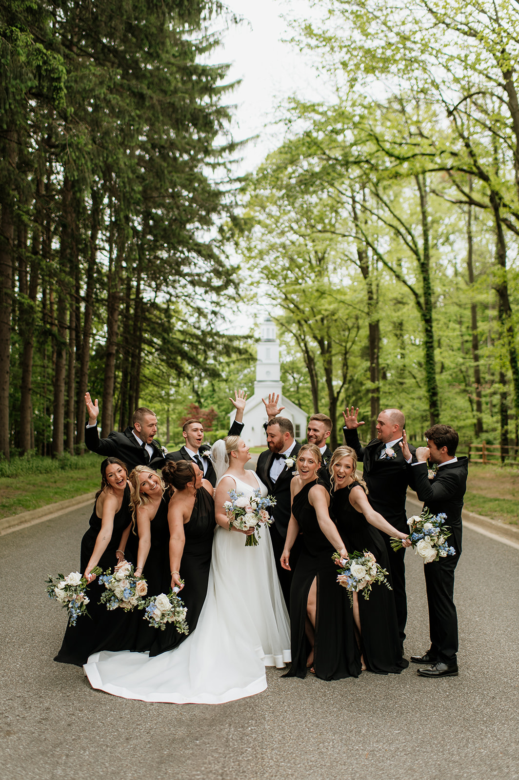 Full wedding part photo on the tree-lined road in front of the chapel at The Morris Estate in Niles, Michigan.